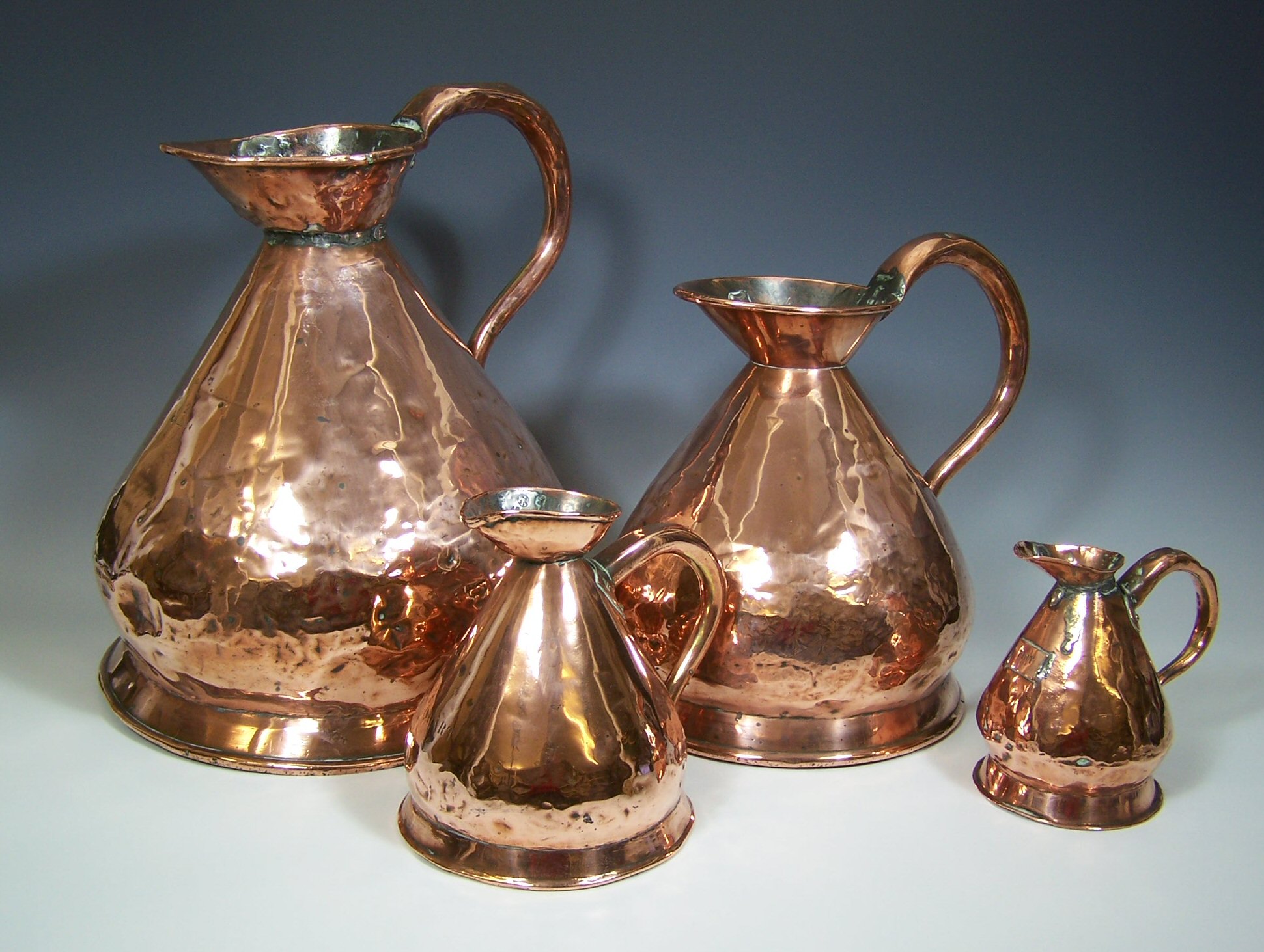 A set of four graduating copper measuring jugs,
