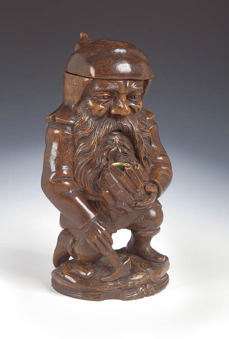 A carved fruitwood tobacco jar carved in the form of a dwarf,