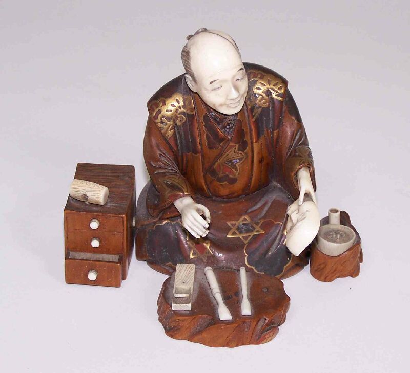 A Japanese carved wood and ivory figure of a kneeling man Meiji period