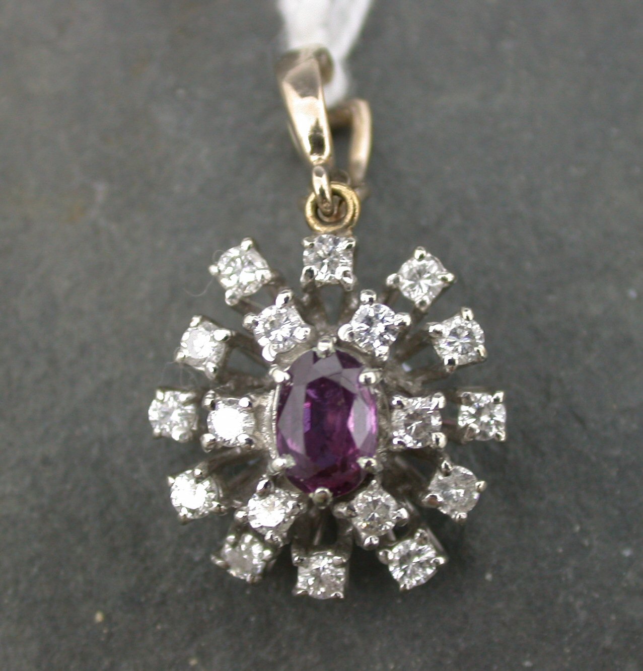 A ruby and diamond oval cluster pendant,