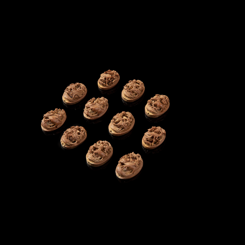 GROUP OF ELEVEN CARVED NUT PLAQUES