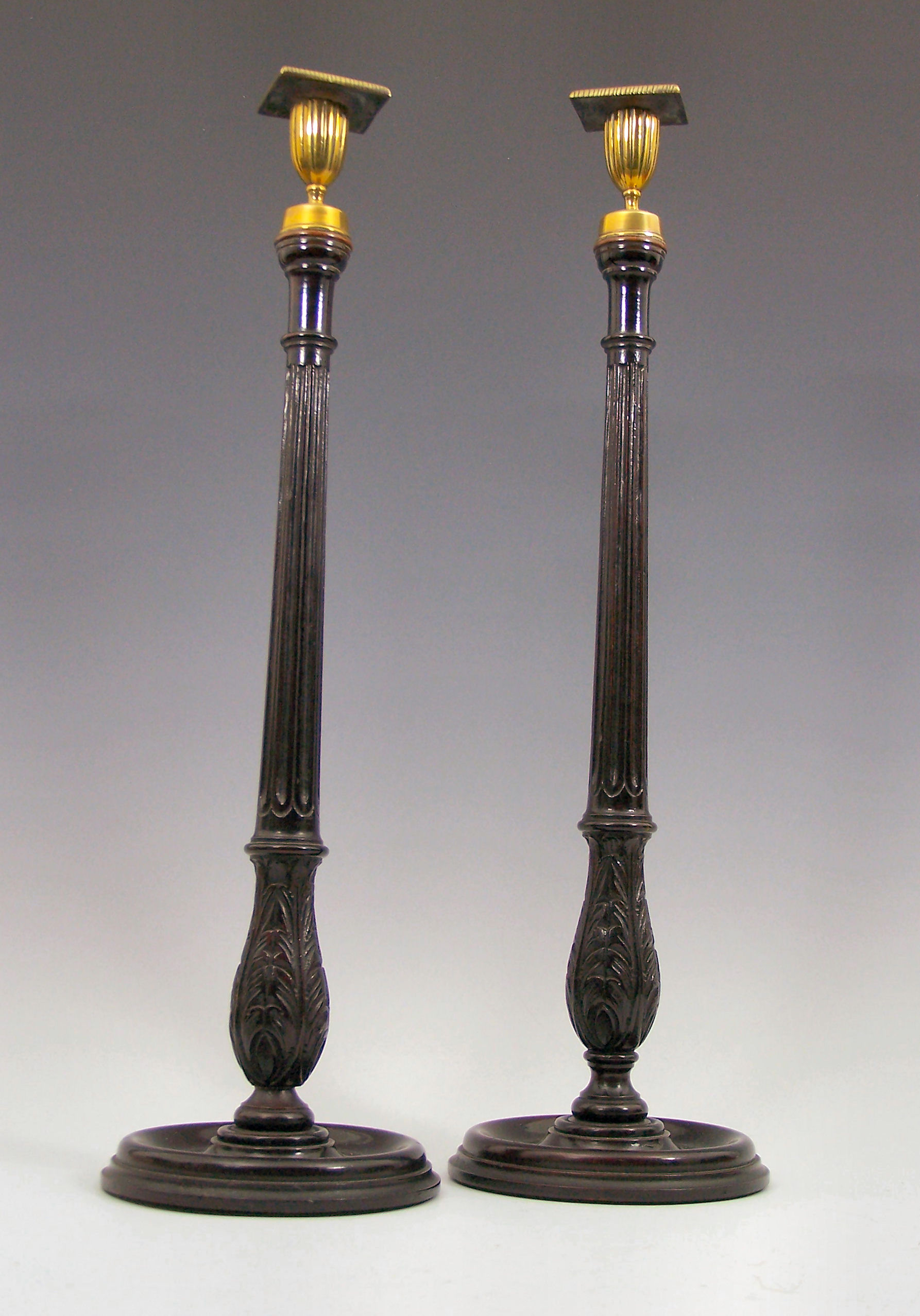 A pair of George III style stained mahogany candlesticks,