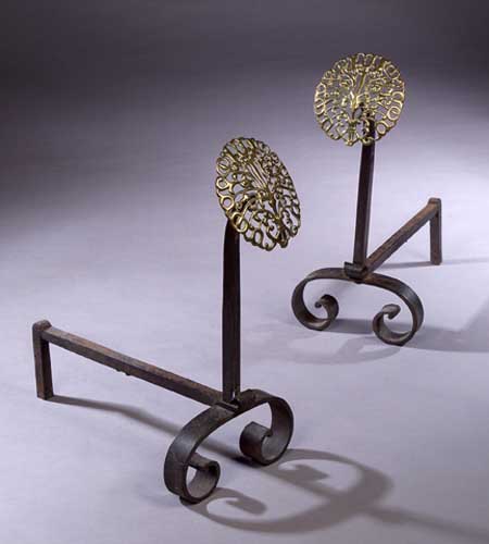 A pair of brass mounted steel fire dogs designed by Edward Spencer
