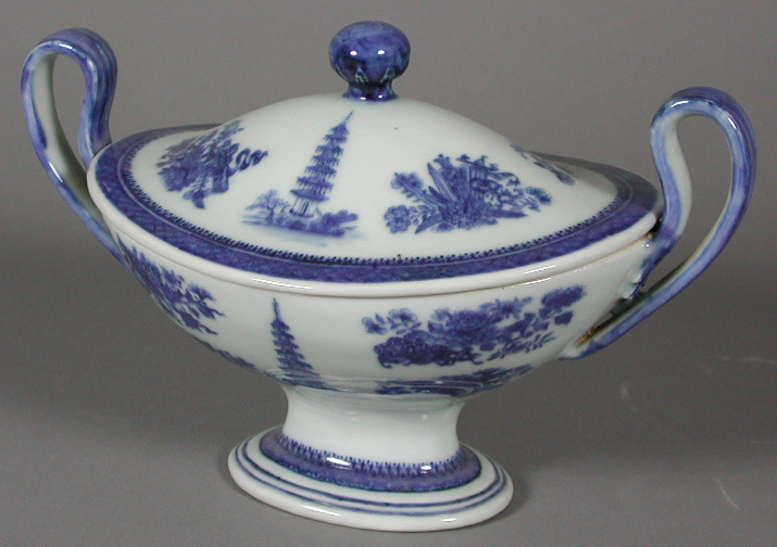 An oval twin handled footed sauce boat and lid