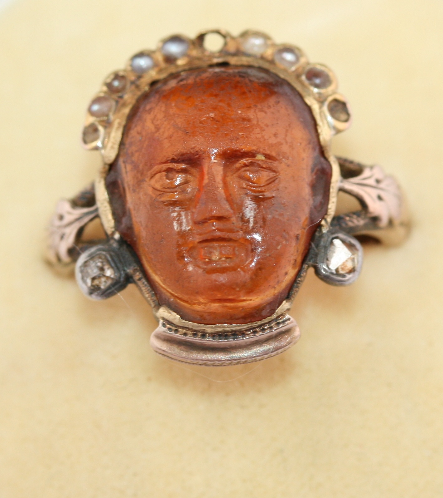 An early 19th century carved hardstone, pearl and diamond set ring