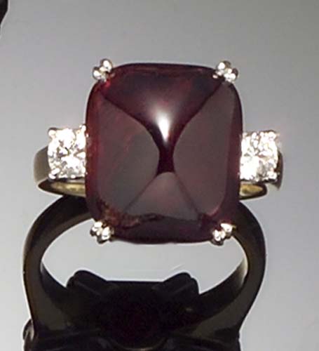 An 18ct gold mounted sugarloaf cabochon ruby and diamond three stone ring,