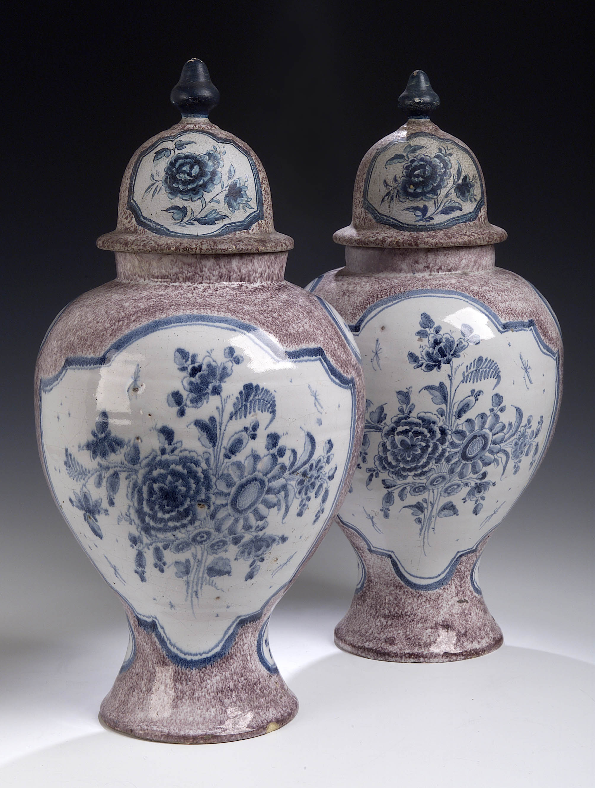 A pair of Dutch Delft manganese ground baluster vases and painted wood lids