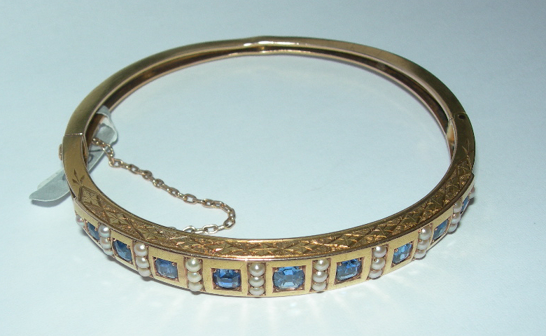 An Edwardian sapphire and seed pearl set bangle,
