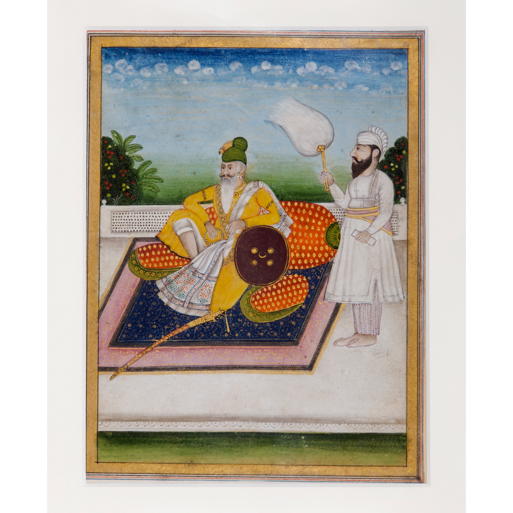 A SIKH SARDAR RECLINING AGAINST BOLSTERS ON A PALACE TERRACE