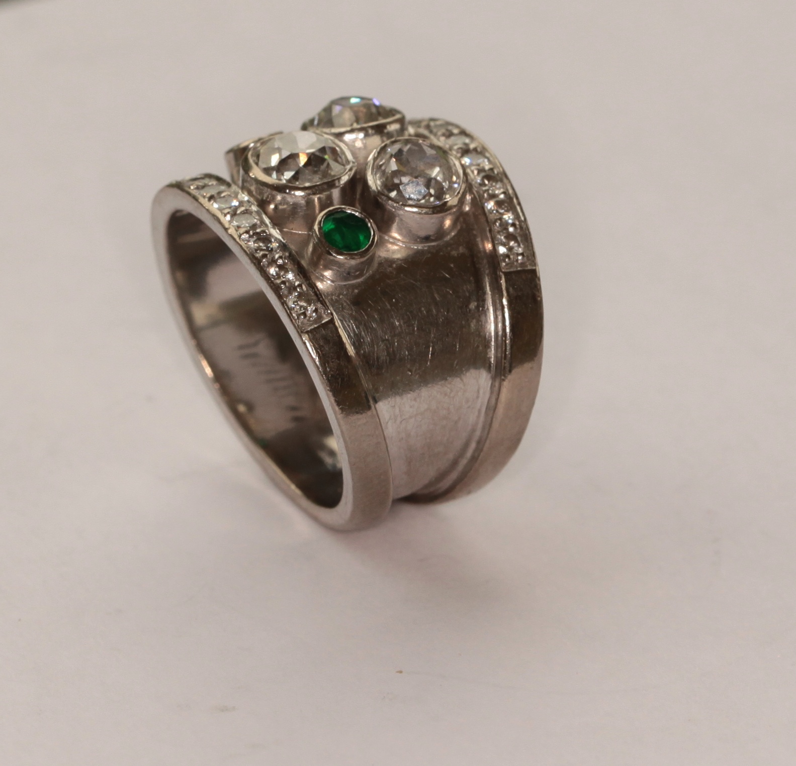 An 18ct white gold abstract diamond and emerald ring