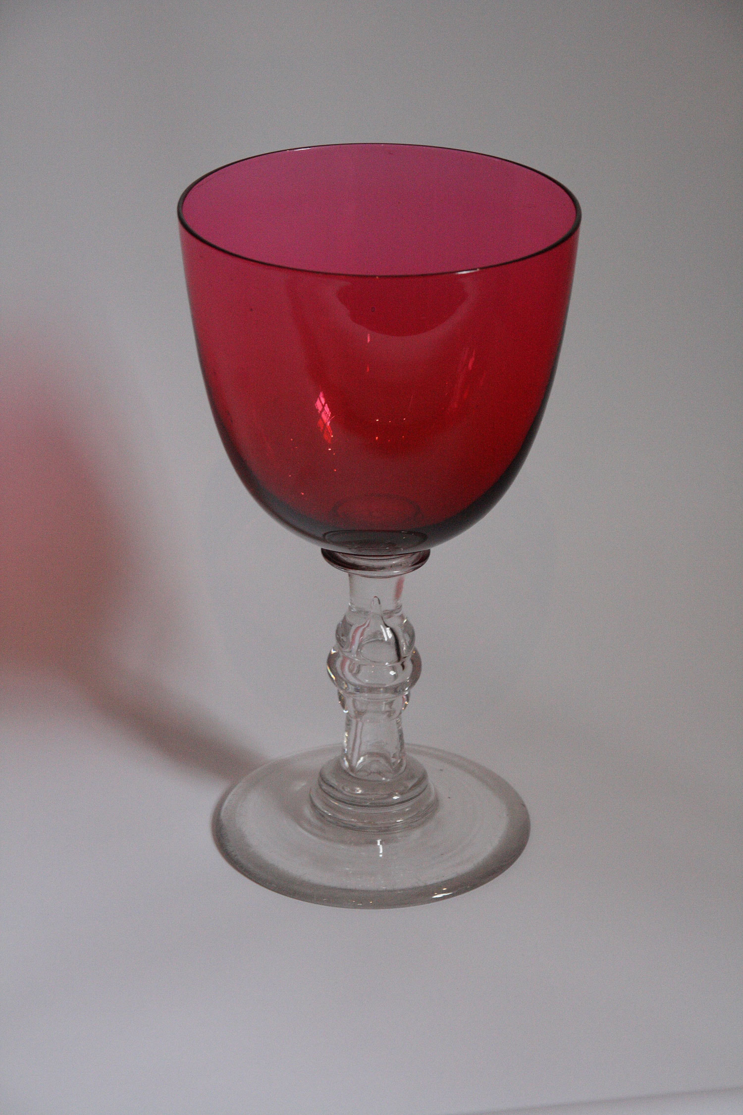 A large cranberry and clear glass goblet