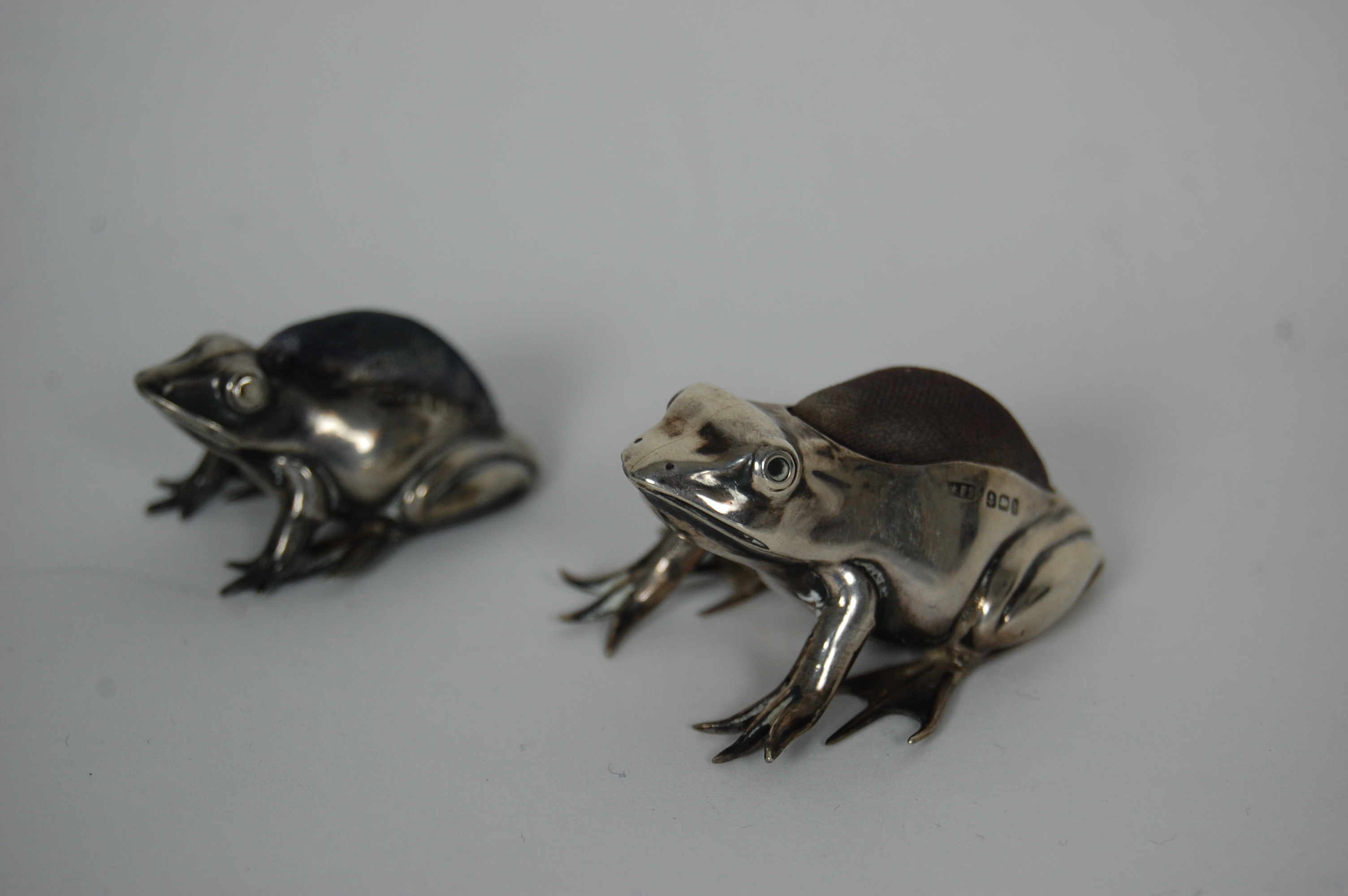 Two silver mounted 'Frog' pin cushions