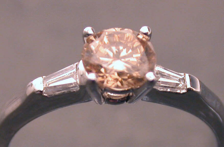 A fancy light orange diamond and platinum ring