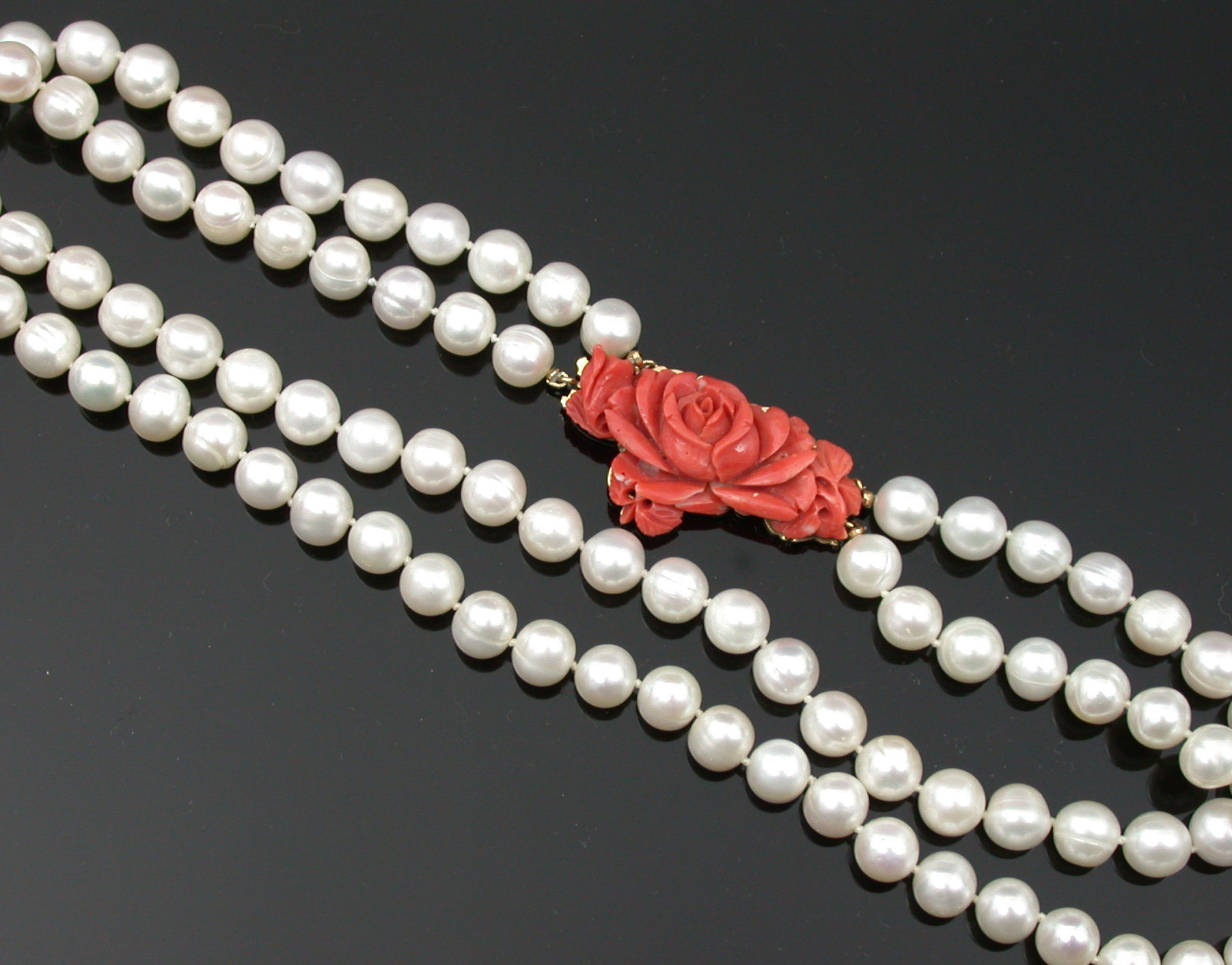 A two-row cultured pearl necklace with carved coral clasp,