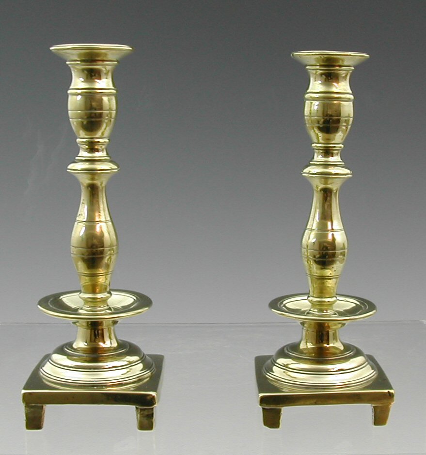 A pair of early 19th century cast brass candlesticks,
