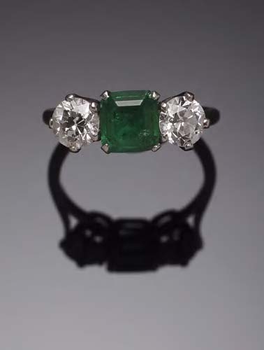 A platinum mounted emerald and diamond three stone ring,
