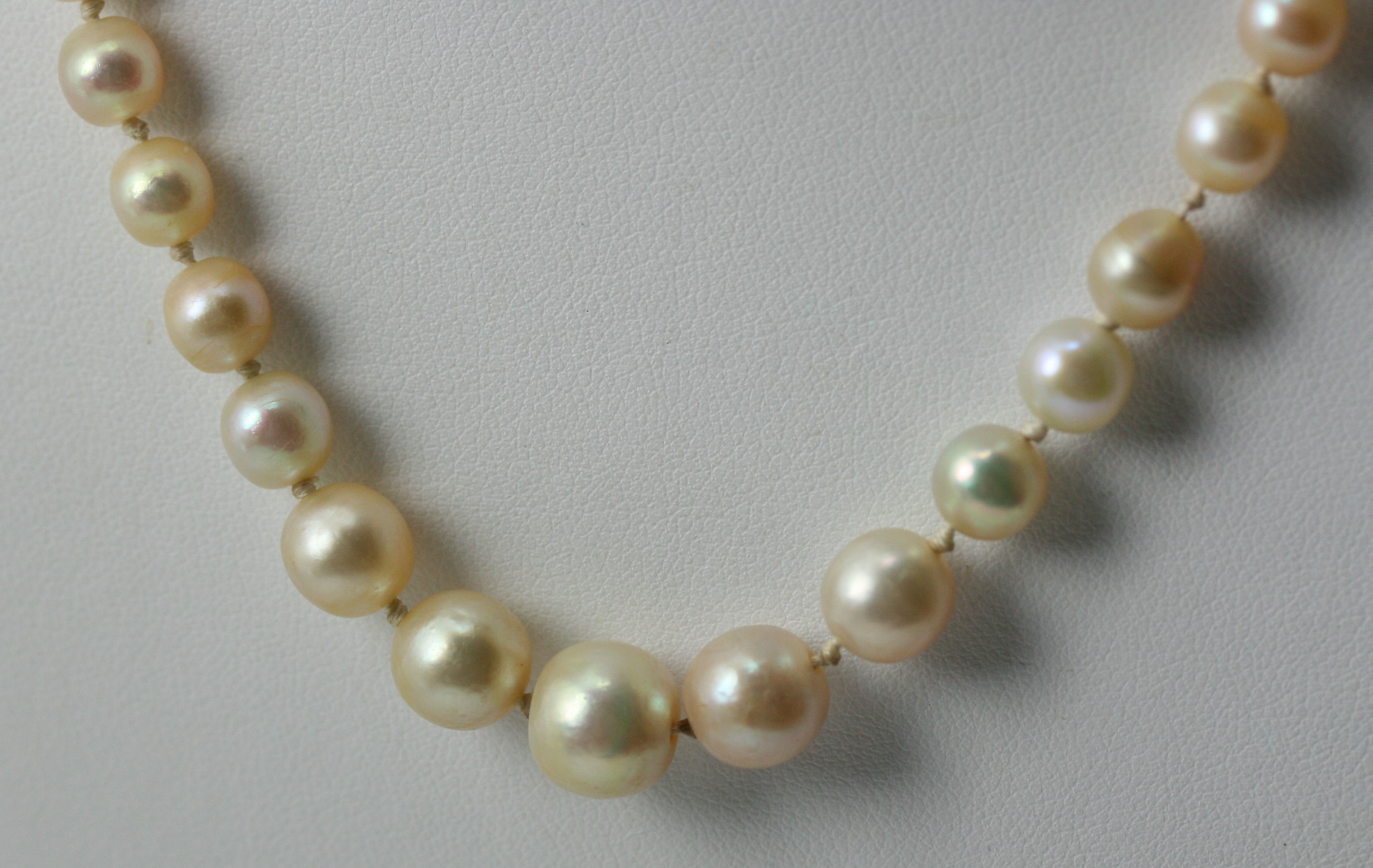 A cultured pearl necklace with red guilloche enamelled and diamond set clasp