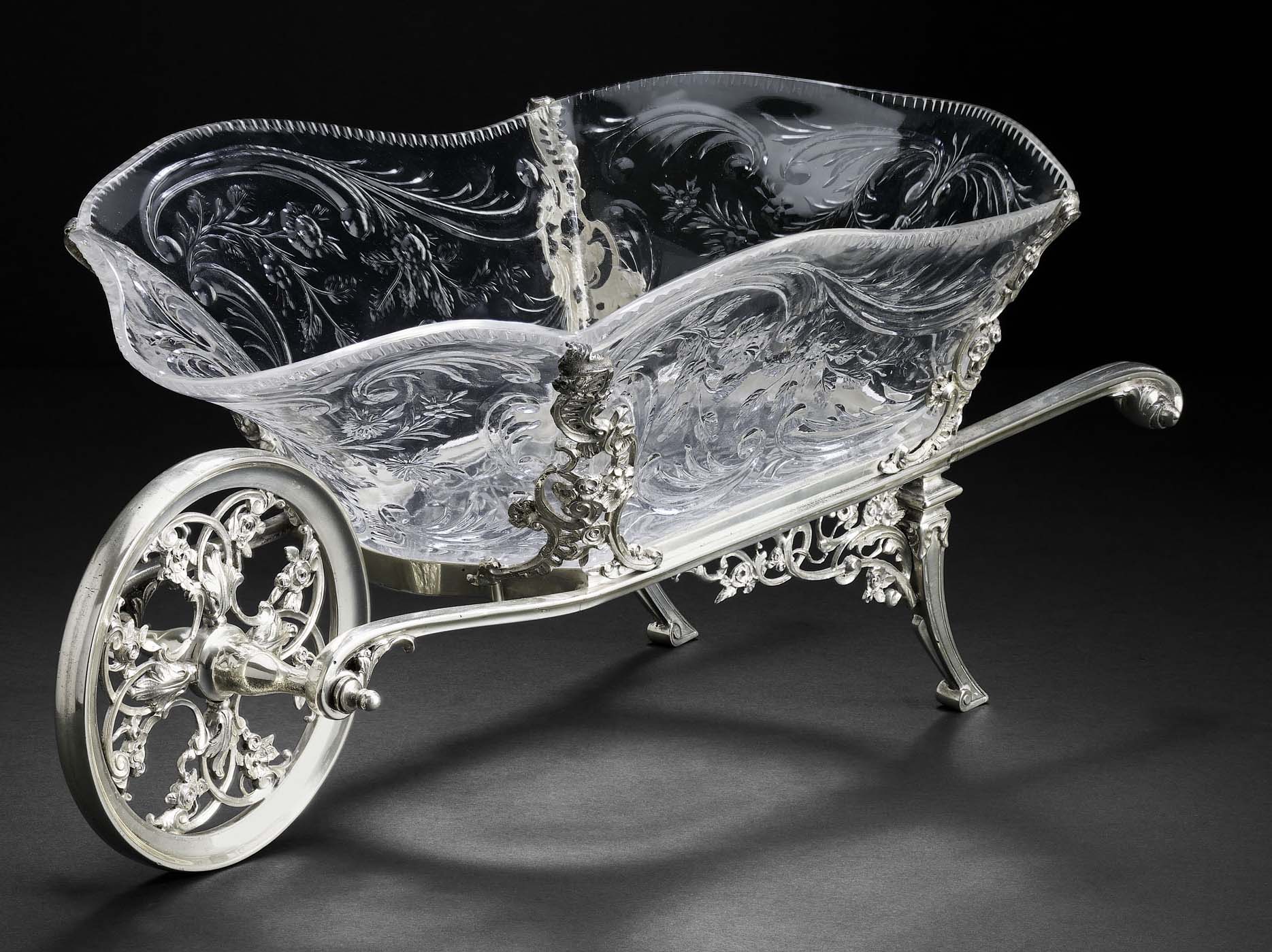 An Edwardian novelty fruit basket in the form of a crystal and silver framed wheelbarrow