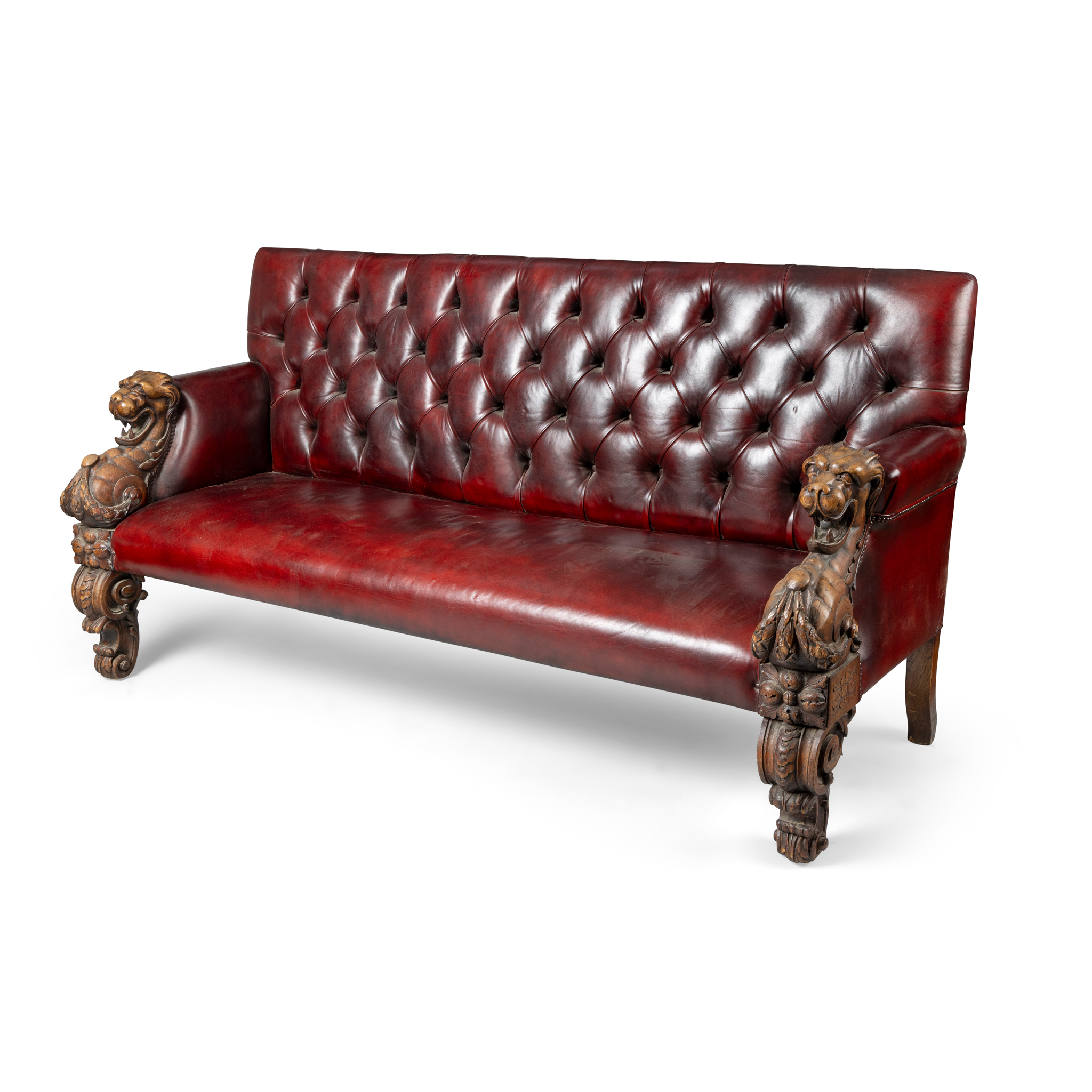 A VICTORIAN CARVED OAK AND RED LEATHER BUTTON BACK SOFA