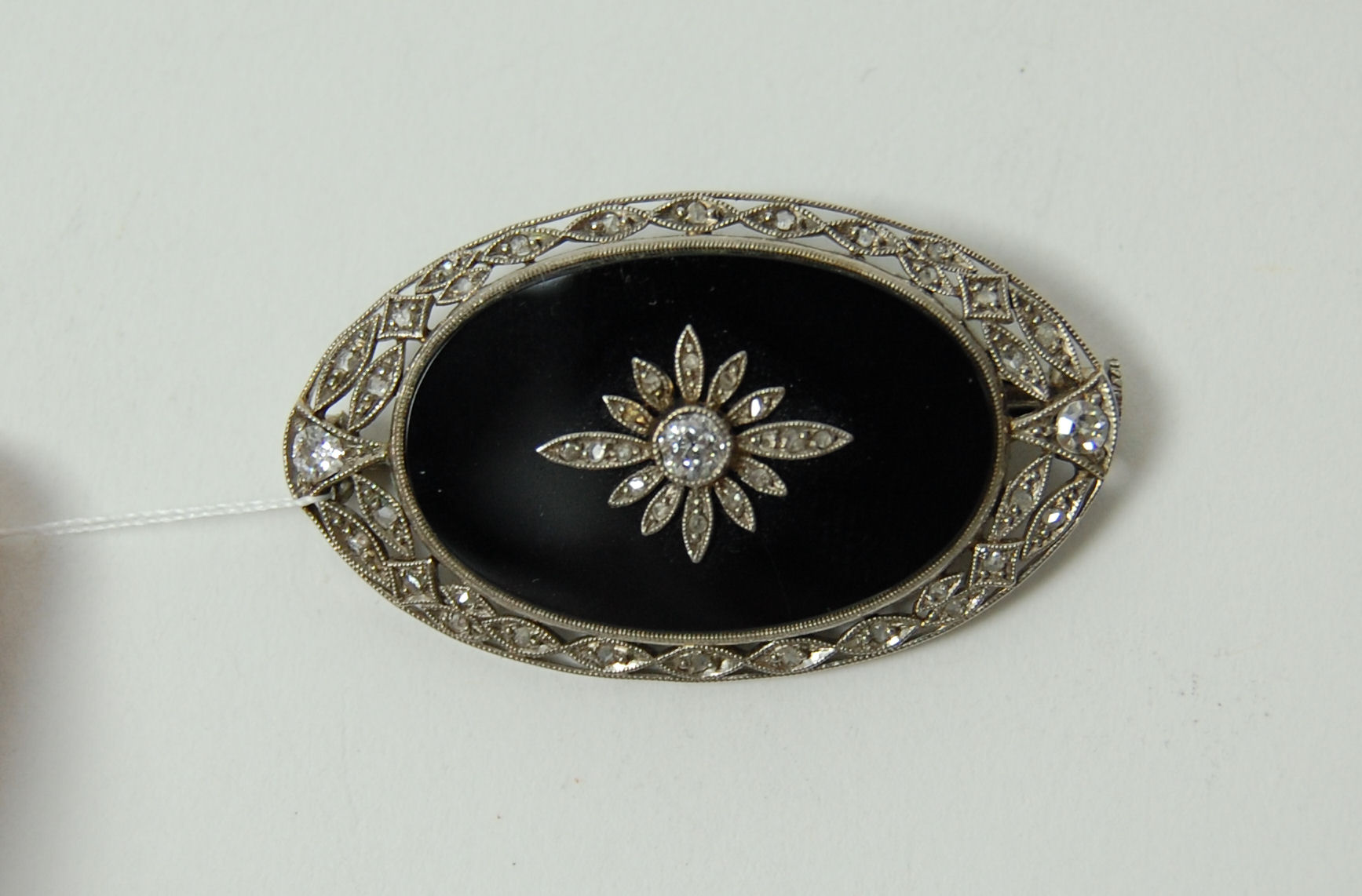 An onyx and diamond set brooch,