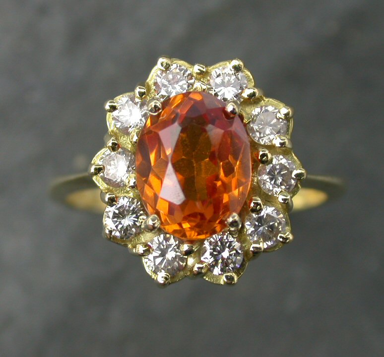 An 18ct gold mounted orange sapphire and diamond cluster ring,