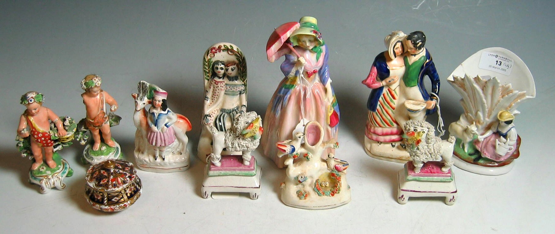 A pair of small Staffordshire figures of poodles with birds;