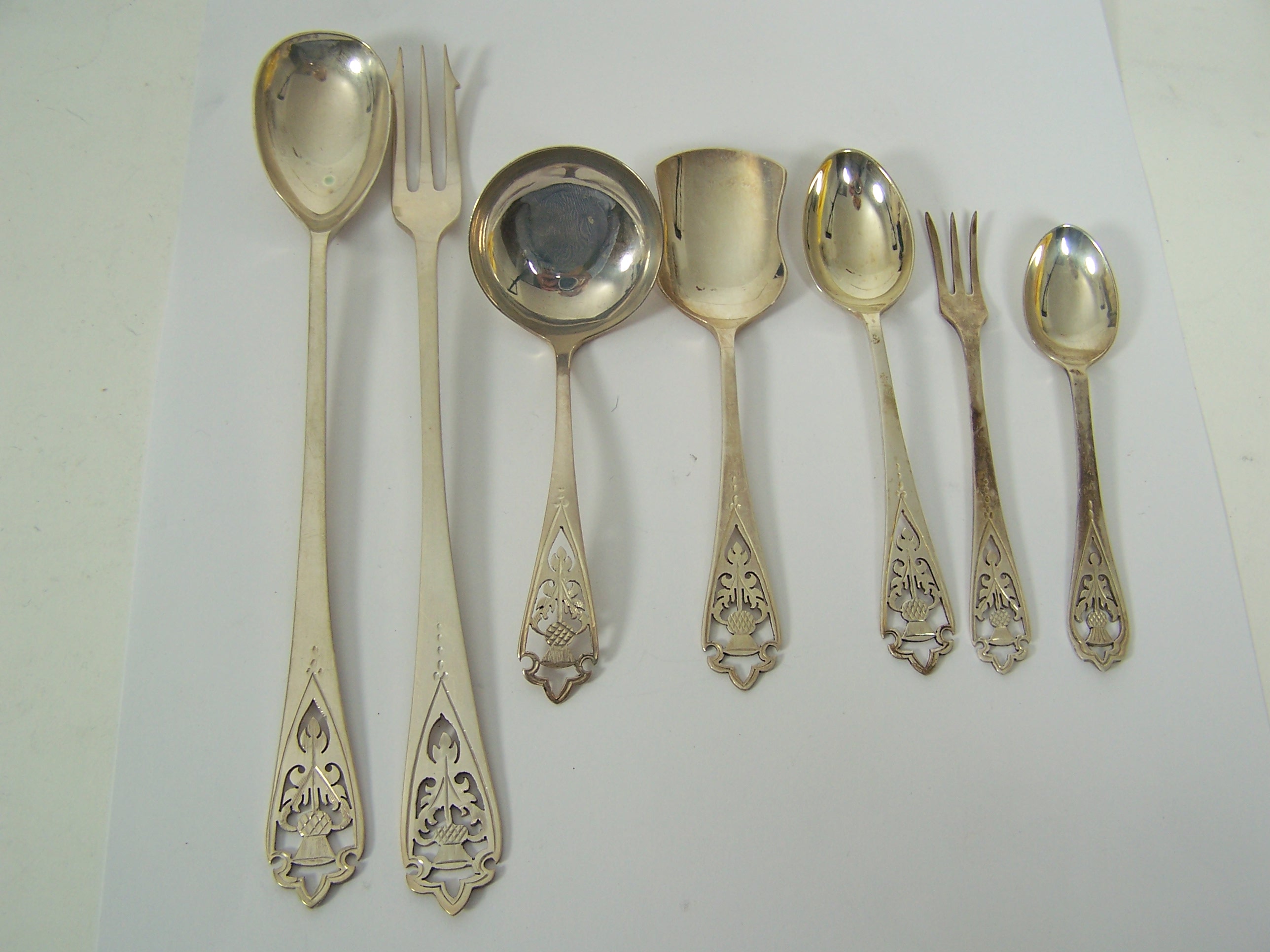 A large collection of pierced thistle spoons