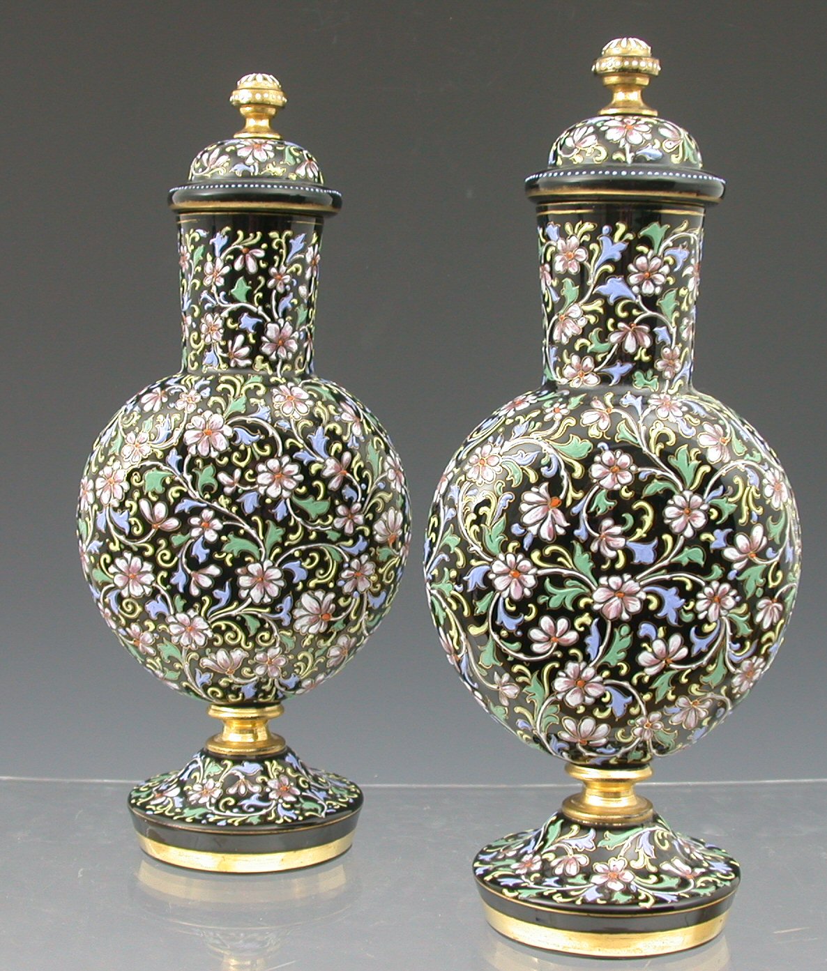 A pair of 19th century Bohemian dark amethyst glass enamelled flasks and covers,