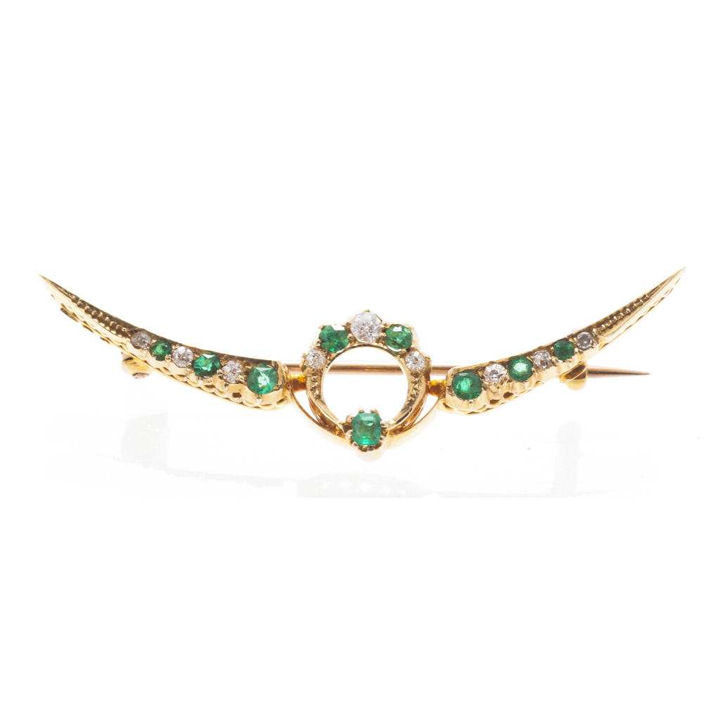 An emerald and diamond set crescent brooch