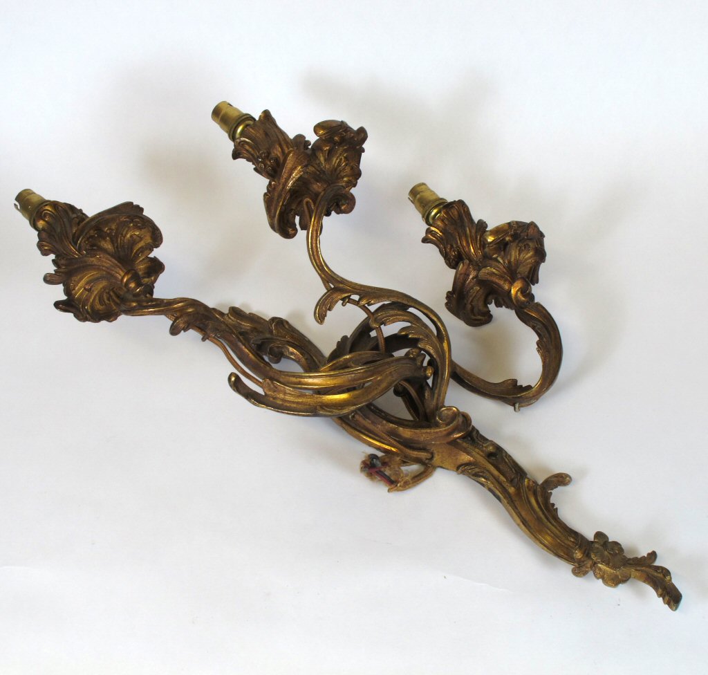 A pair of gilt metal three branch rococo style wall sconces