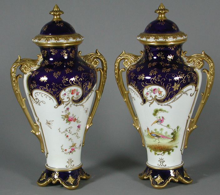 A pair of Coalport tapered baluster twin handled vases and covers