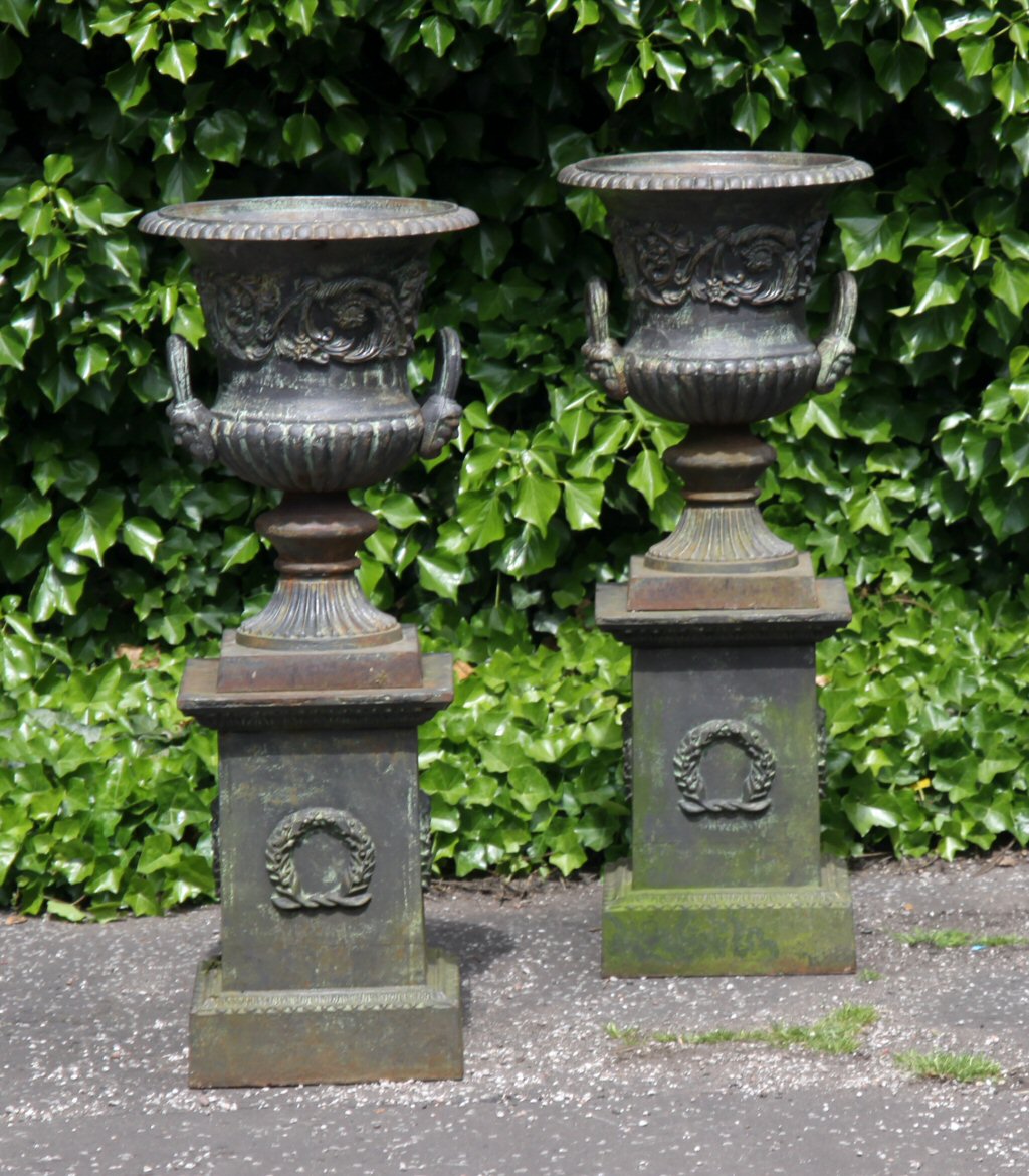 A pair of 19th century cast iron garden urns and plinths