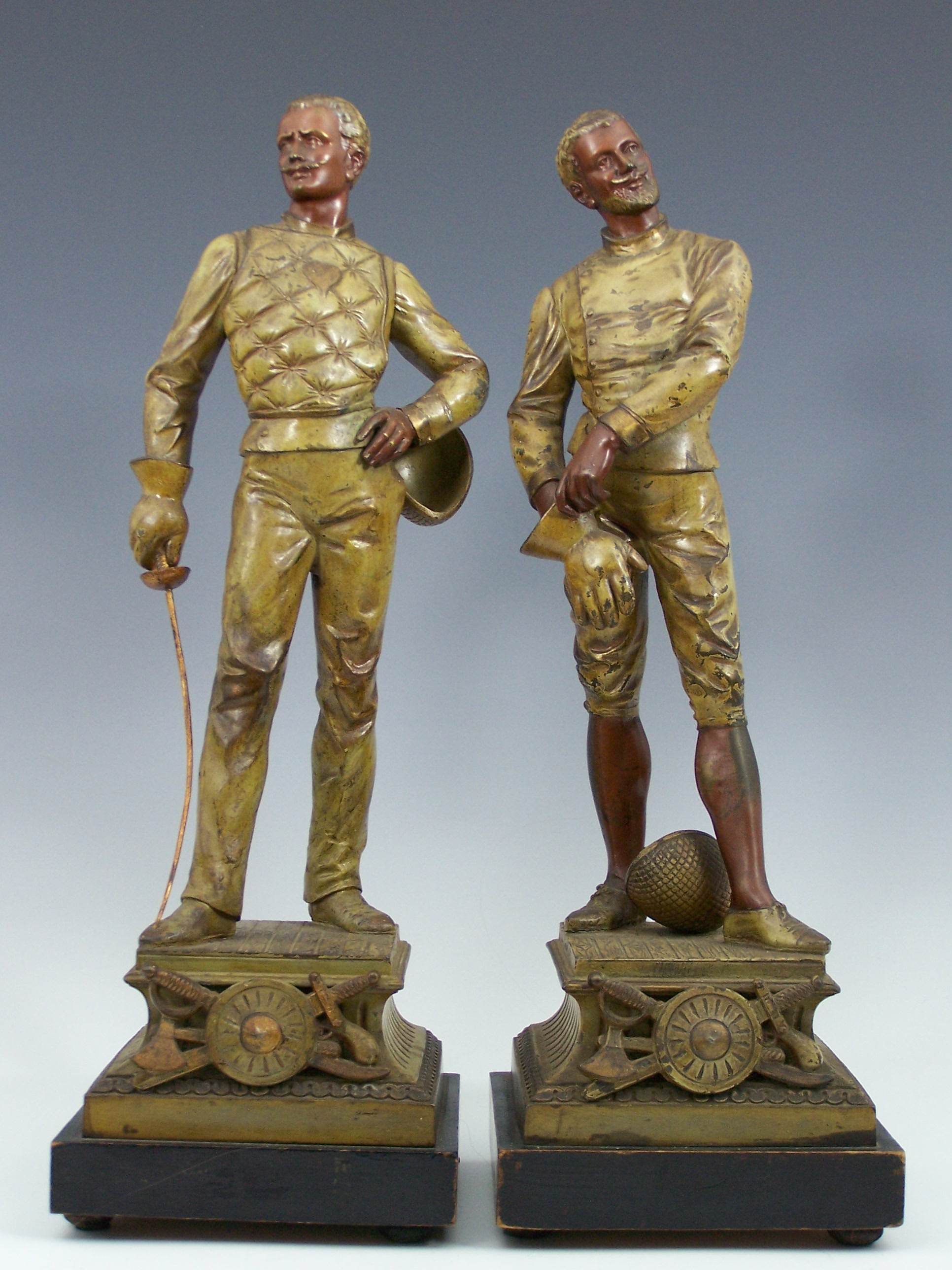 A pair of painted spelter figures of opposing gentlemen fencers, after L Raphael,