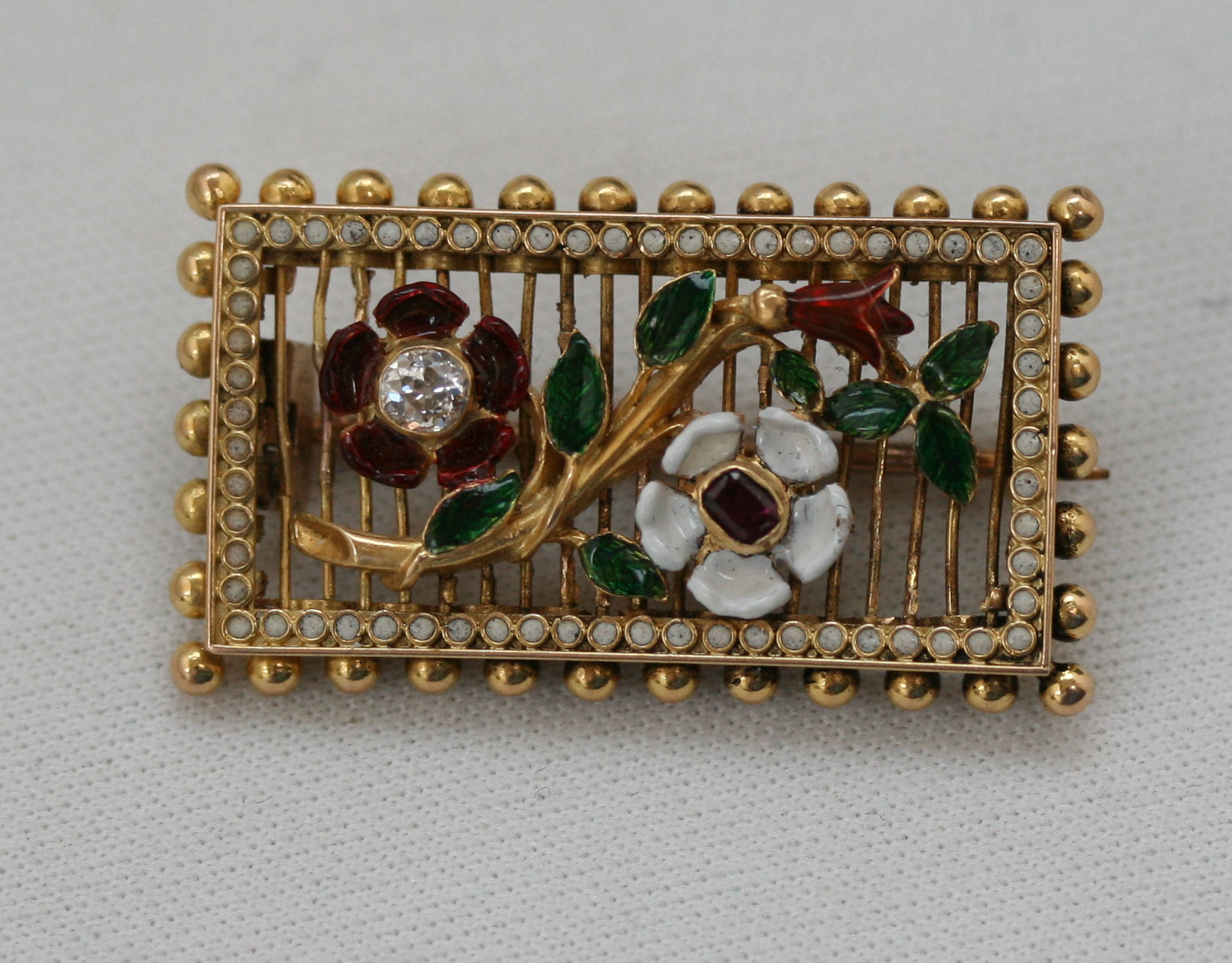 An early 20th century enamel decorated ruby and diamond set brooch,