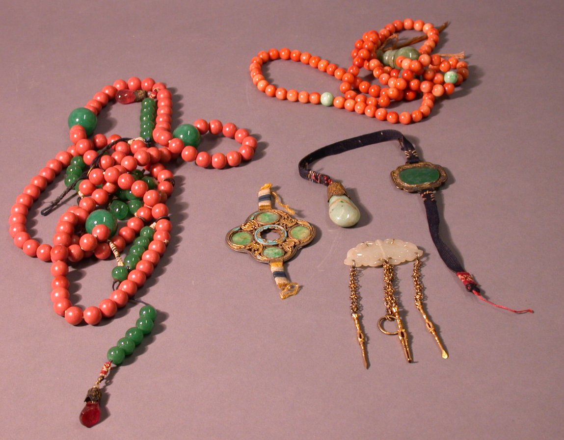 A Chinese carved pale celadon jade stylised butterfly shaped pendant with three gilt brass acessories