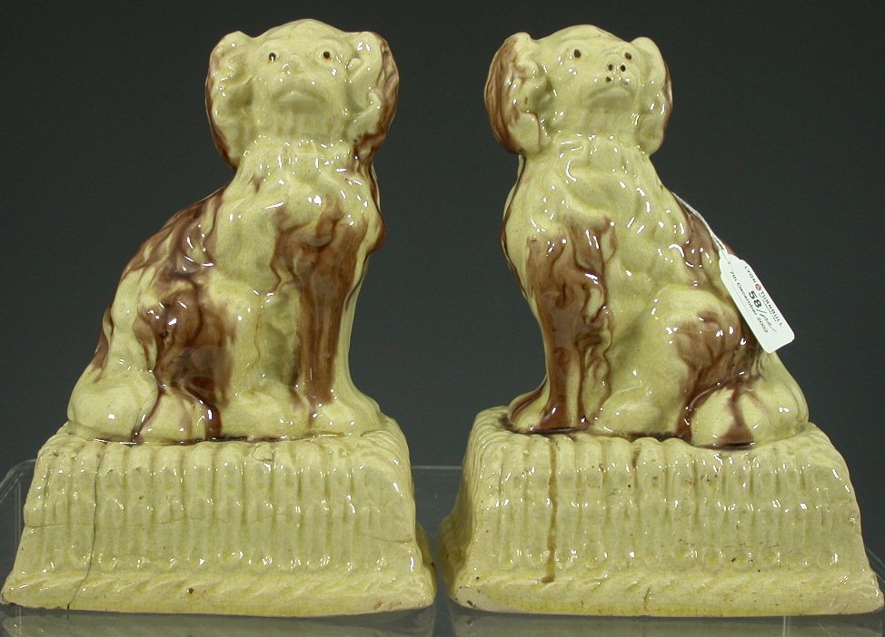 A pair of early 19th century pottery dogs on stands