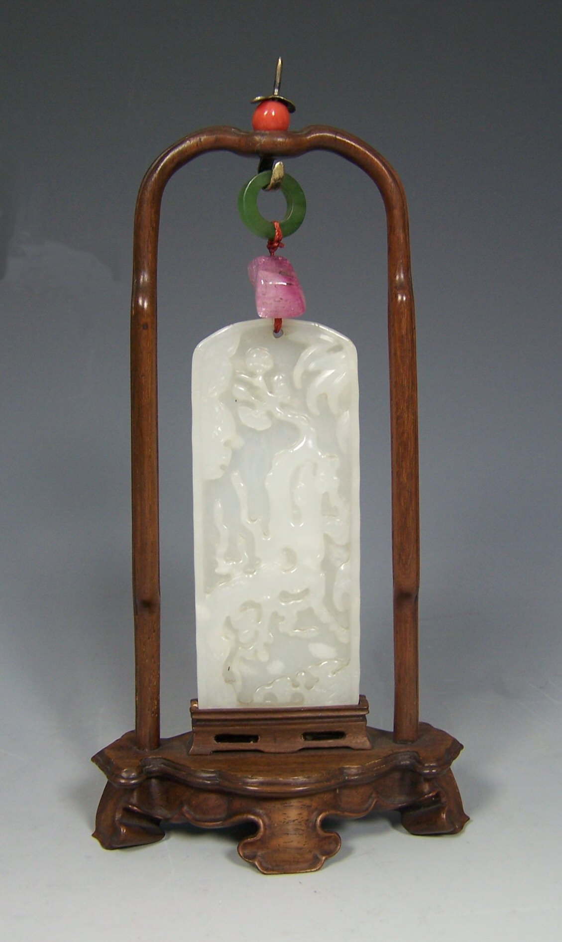 A carved white jade pendant in stand