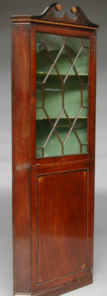An early 19th century mahogany corner cupboard