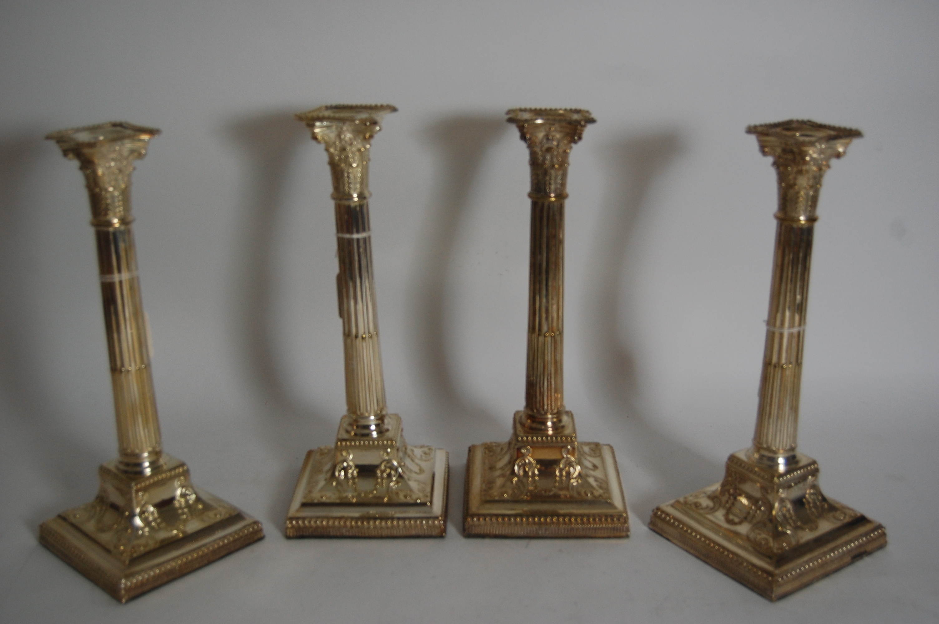 A set of four plated corinthian column candlesticks