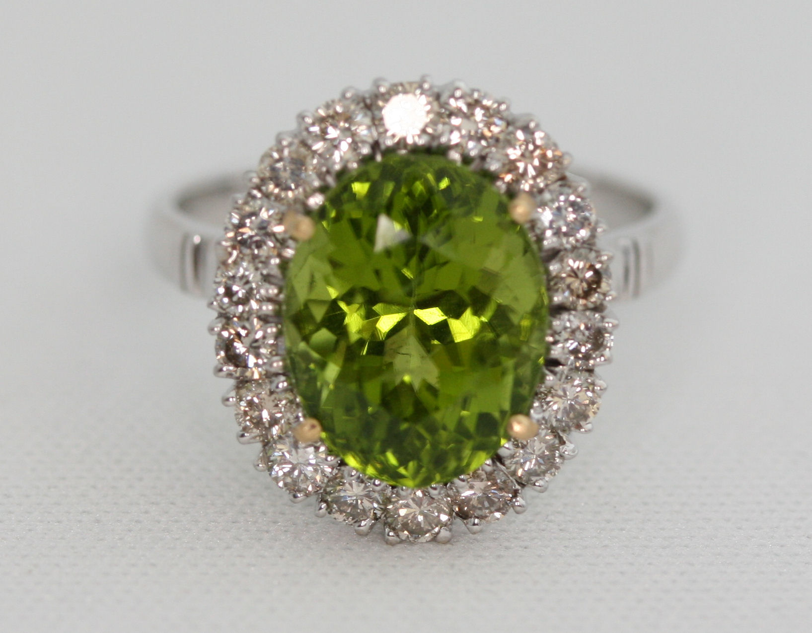 A modern 18ct white gold mounted peridot and diamond cluster ring,