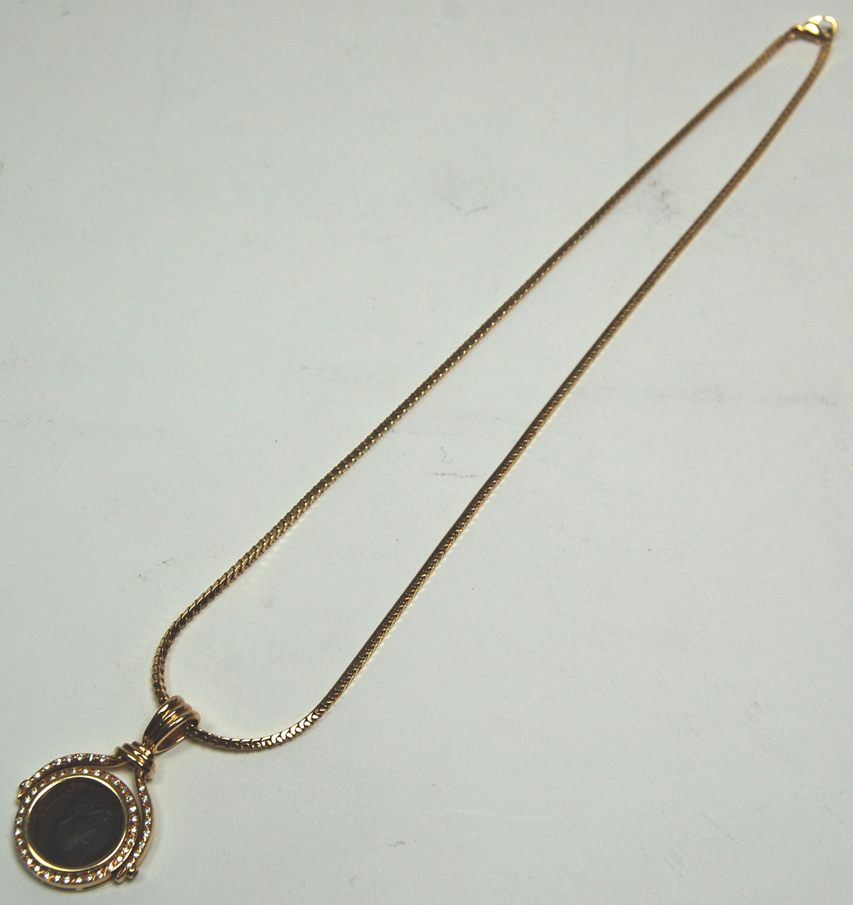 A modern diamond and coin set pendant with chain,
