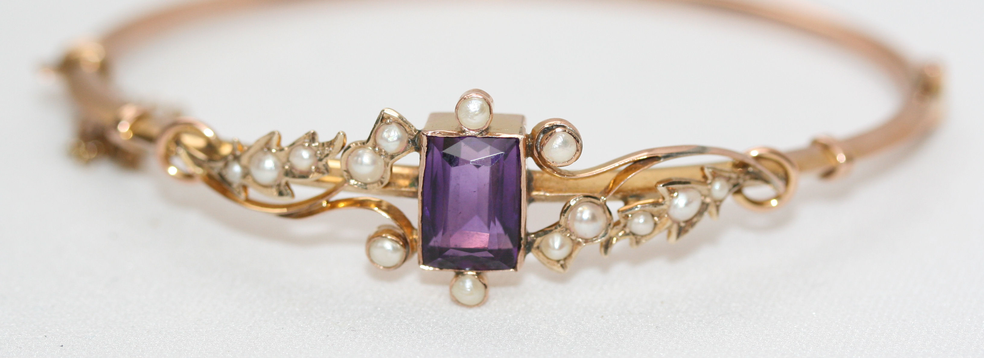 An Edwardian gold, pearl and amethyst hinged bangle