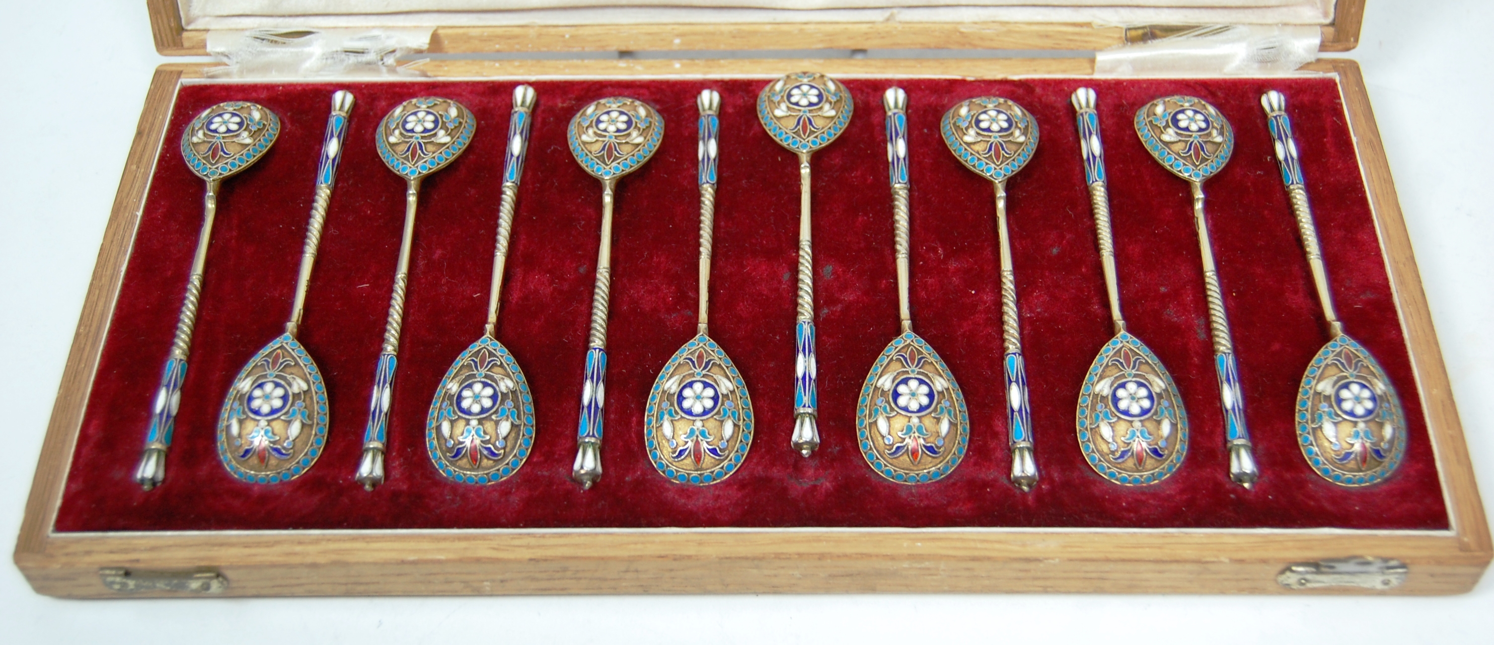 A cased set of Russian silver gilt and champleve spoons
