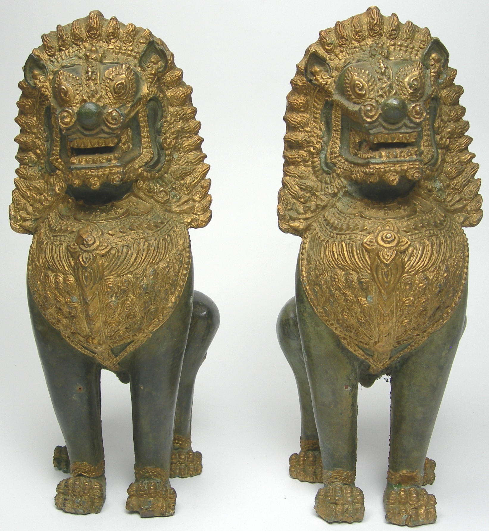 A pair of South East Asian giltmetal and stone lions