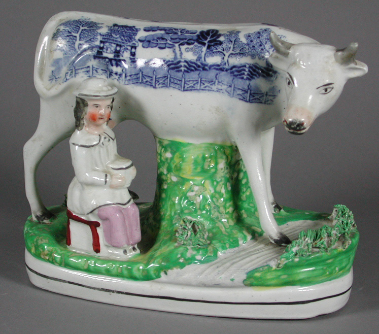 A Staffordshire figure of a cow and a seated milk maid