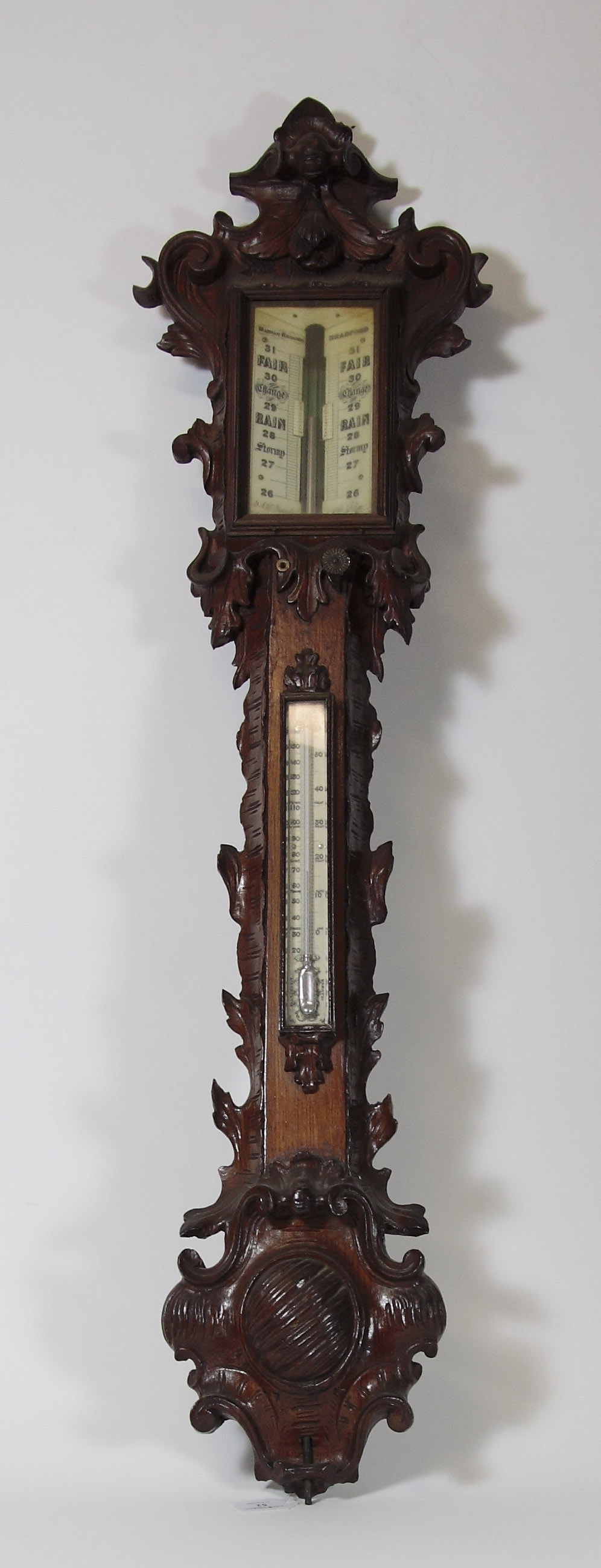 A carved oak stick barometer The dial marked Manoah Rhoades, Bradford