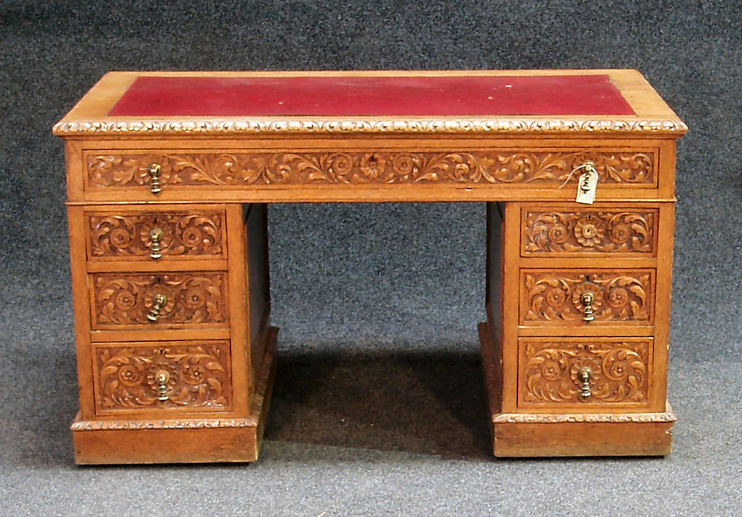 A late Victorian carved oak twin pedestal desk,