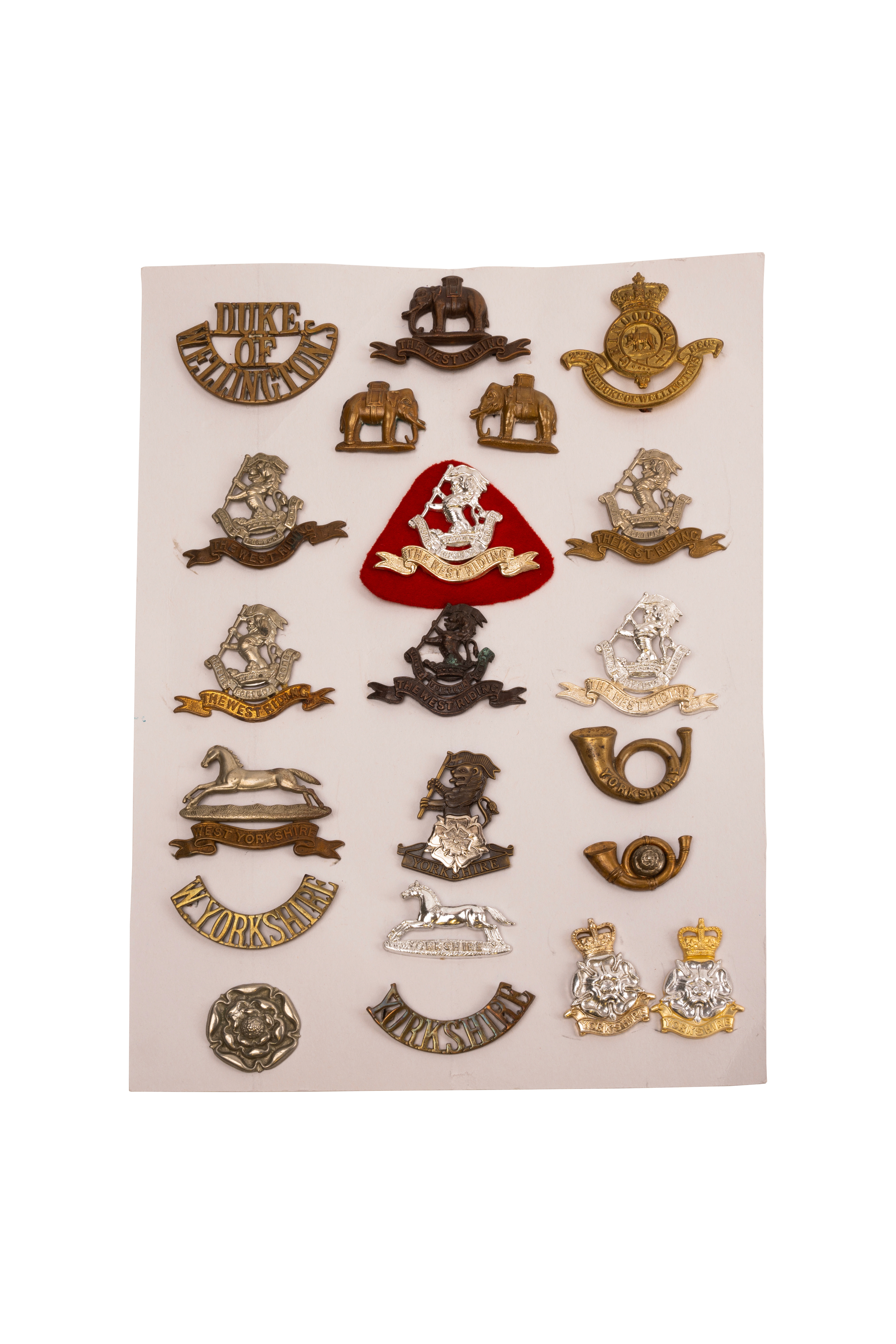 21 British cap and collar badges and shoulder titles, mounted on card