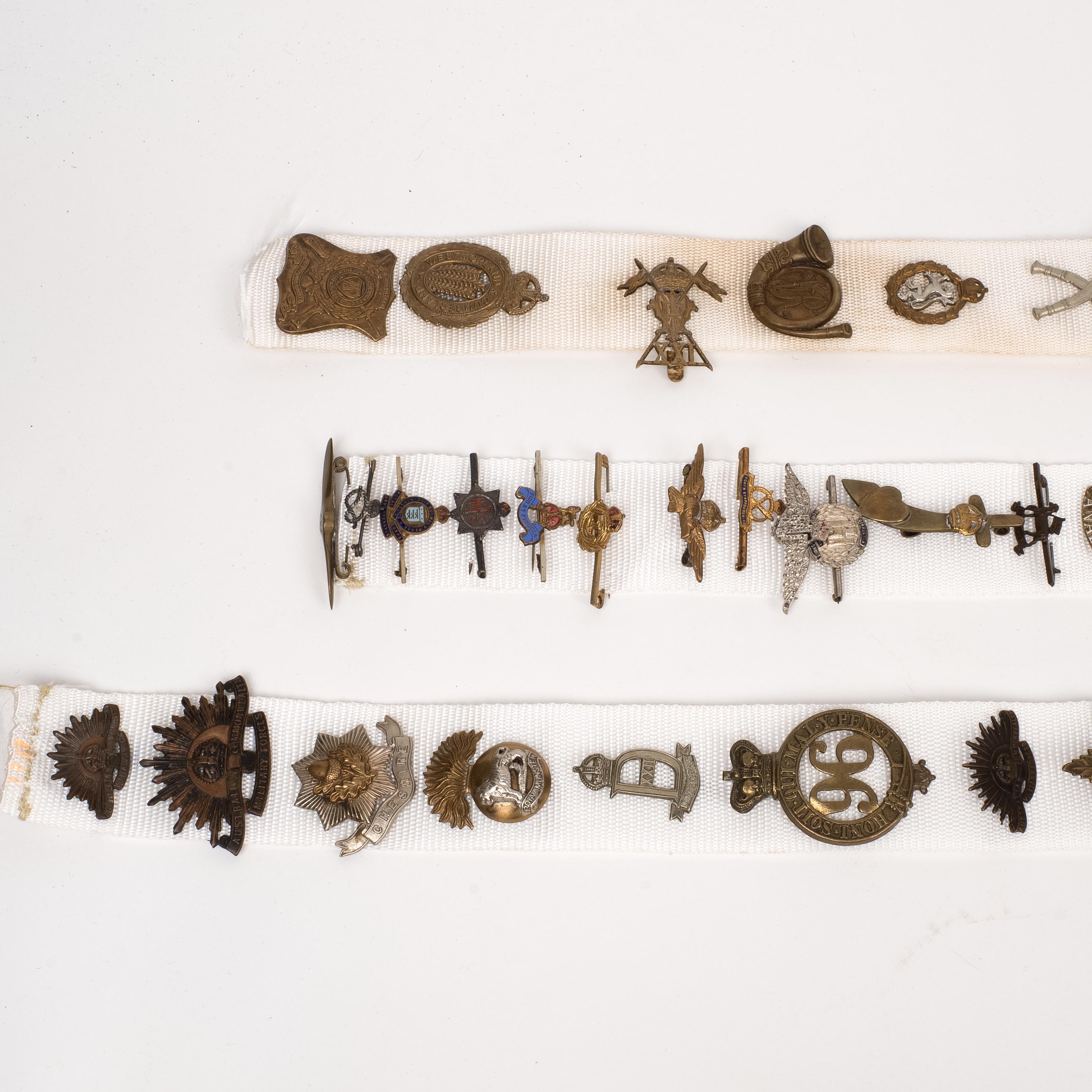 32 British Cap Badges and 30 Tie Pins, mounted on cloth strips 