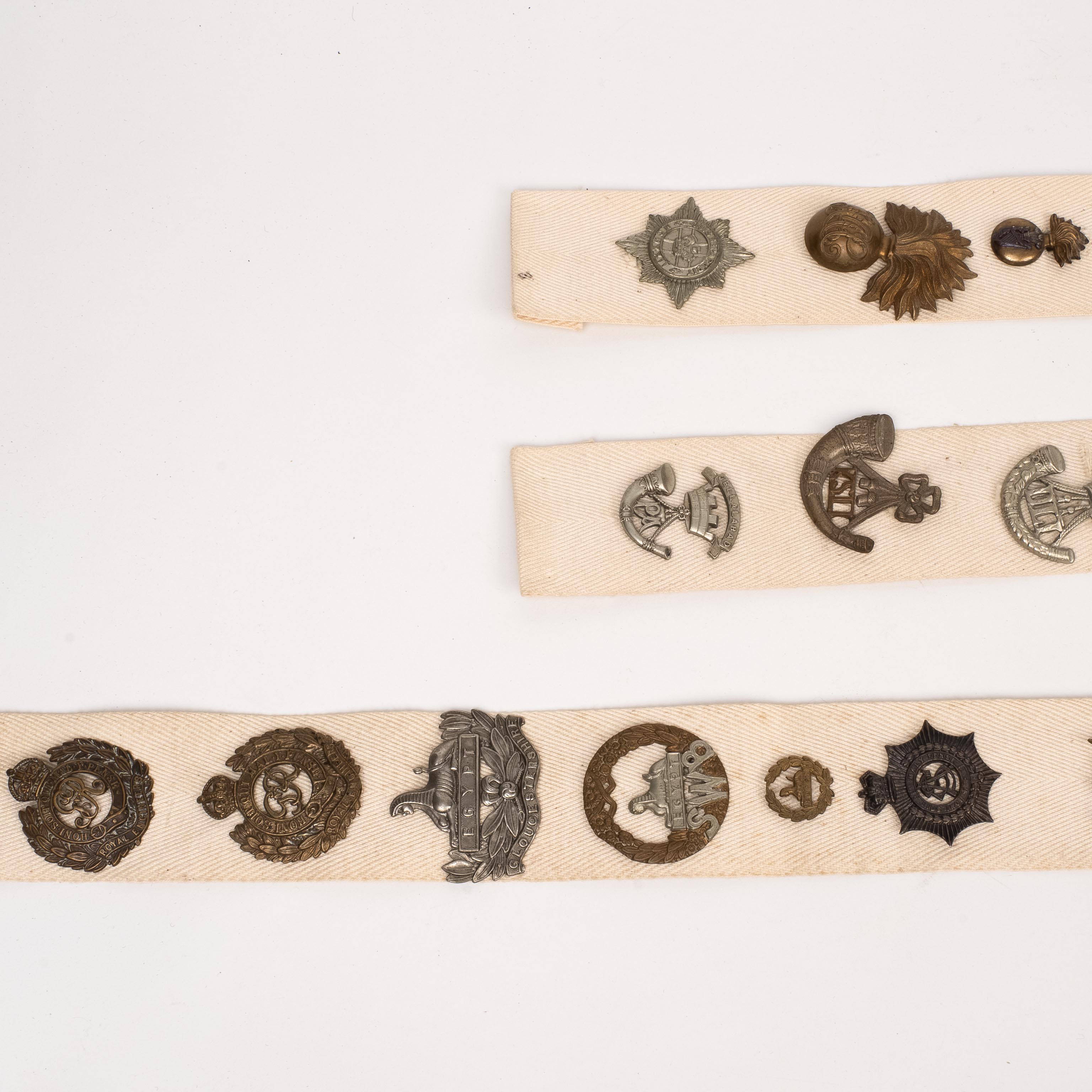 38 British Cap Badges, mounted on cloth strips